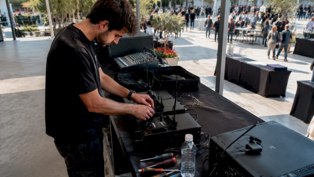 Un tecnico audio si occupa di sistemare tutta l’attrezzatura in vista della conferenza.