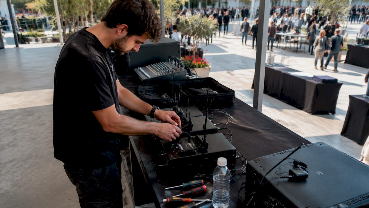 Un tecnico audio si occupa di sistemare tutta l’attrezzatura in vista della conferenza.