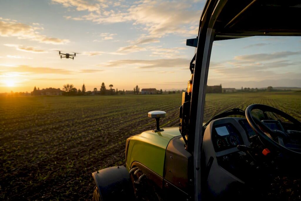 Dettaglio della plancia di un trattore moderno, mentre un drone sorvola il campo.