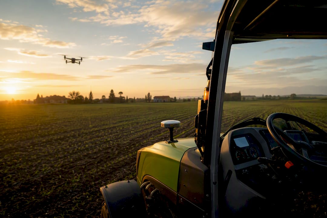 Dettaglio della plancia di un trattore moderno, mentre un drone sorvola il campo.