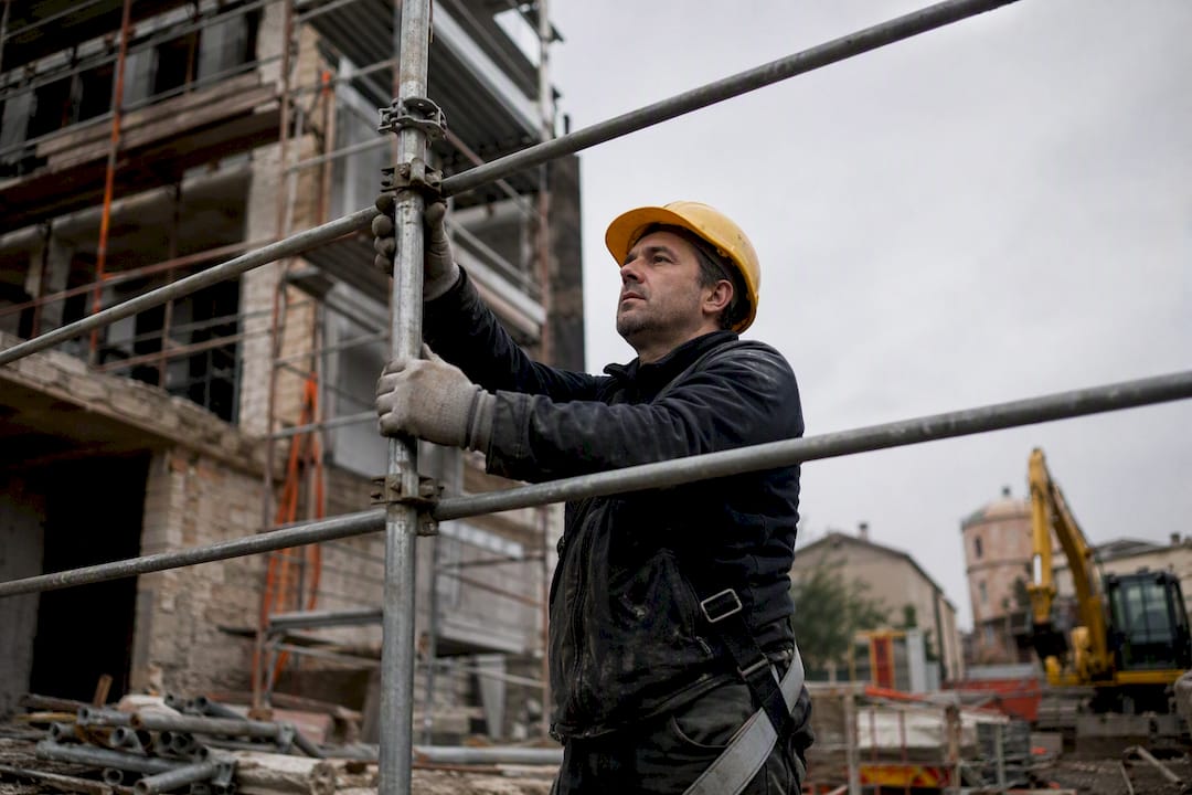 Operaio che monta un ponteggio in un cantiere edile